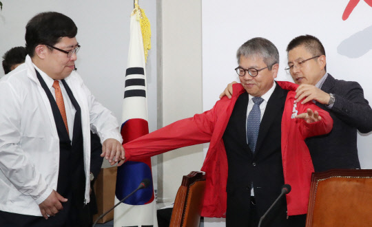 황교안 한국당 대표(오른쪽)가 31일 국회에서 열린 '제1차 영입인재 환영식'에서 김용하 순천향대 IT금융학과 교수에게 점퍼를 입혀주고 있다.    연합뉴스
